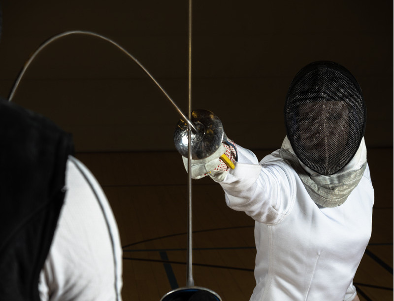 Dieses Foto zeigt eine Schülerin,- die mit einem Florett auf die Brust ihres Trainers stößt.